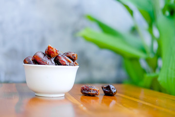 Bowl white with delicious dried dates isolated on wooden board brown.