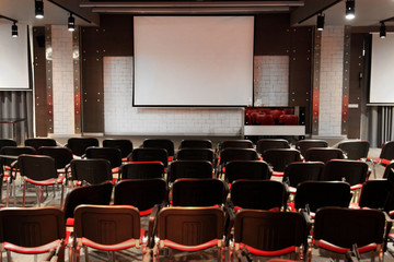 lecture hall / conference room with red chairs and screen