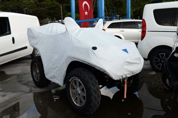 Quad bike under a protective cover in a Parking lot in the Turkish city of Marmaris