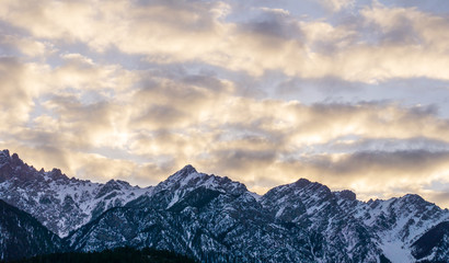 close-up view of the mountain peak with trees and snow on it sunset time.
