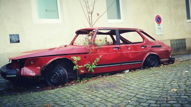 Side View Of An Abandoned Car Against Wall