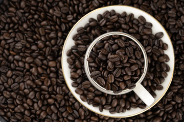 Top view of coffee cup with roasted beans on coffee beans background
