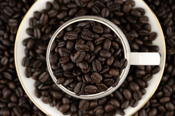 Top view of coffee cup with roasted beans on coffee beans background