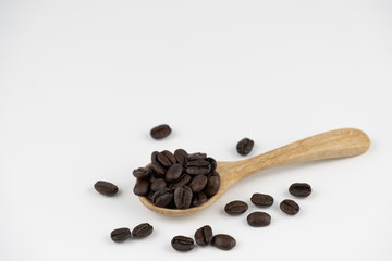 Roasted coffee beans on wooden spoon on white background