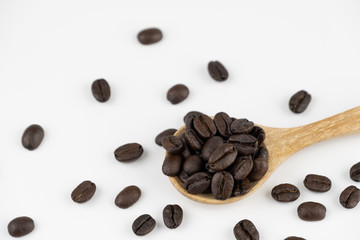 Roasted coffee beans on wooden spoon on white background