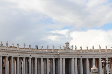 A group of Saint Statues on the colonnades of St Peter's Square with blue sky and clouds in Vatican...