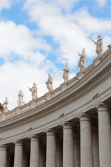 Fototapeta na wymiar A group of Saint Statues on the colonnades of St Peter's Square with blue sky and clouds in Vatican City, Rome, Italy