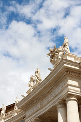 Fototapeta na wymiar A group of Saint Statues on the colonnades of St Peter's Square with blue sky and clouds in Vatican City, Rome, Italy