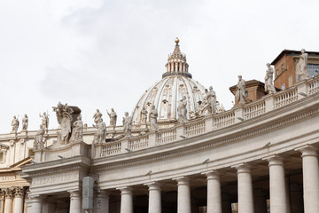 Fototapeta na wymiar A group of Saint Statues on the colonnades of St Peter's Square with dome in Vatican City, Rome, Italy