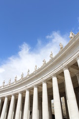 A group of Saint Statues on the colonnades of St Peter's Square with blue sky and clouds in Vatican...