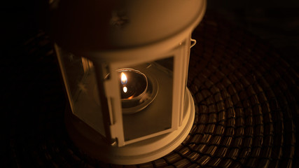 Lit lantern with a candle on dark background. Close up