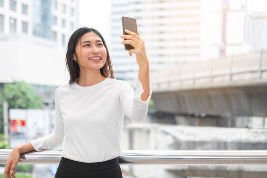Portrait of young Asian beautiful woman taking selfie with smartphone in street city of Bangkok Thailand