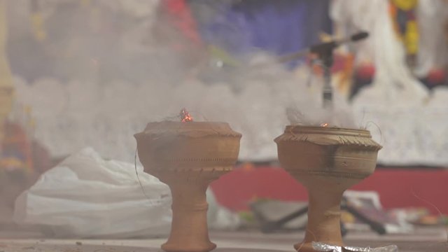 Dhunachi emitting incense during pujo, used for dance and aarti in Durga Puja, with idol in the background in Kolkata, West Bengal