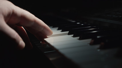 Hands play on the piano. The palm lies on the keys and plays the keyboard instrument. Hand pianist. Black dark background.