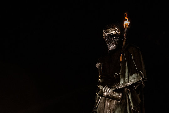 Estatua de Sim&oacute;n Bol&iacute;var con antifaz y antorcha en el brazo en una protesta social