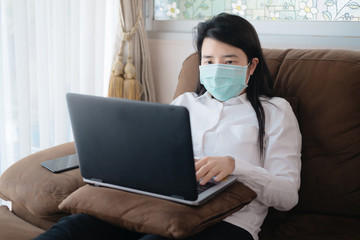 Fototapeta na wymiar Asian women use laptop in working at home and wearing mask for protect COVID-19