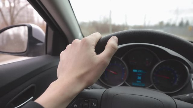 Driver's Hand On The Steering Wheel Of A Car Travelling On The Road At Daytime - Closeup Shot