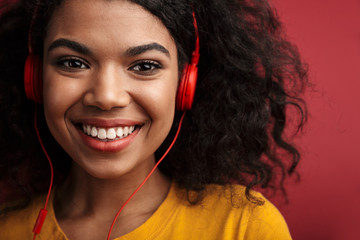 Cheery young african woman listening music with headphones.