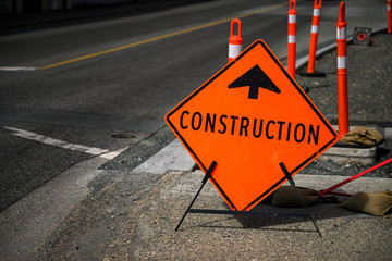 Bright orange construction sign on the street warns the traffic