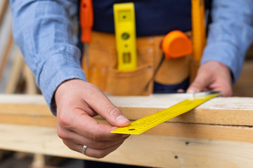 Carpenter's hands measuring plank