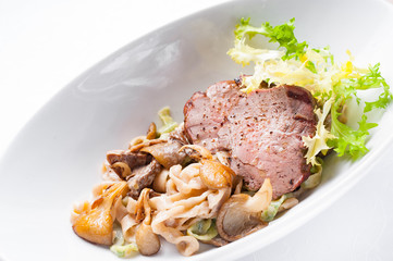 Pasta with meat and mushrooms. White plate on a white background.