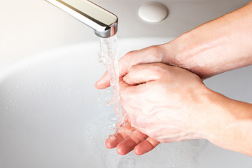  Washing hands under a stream of water  in the bathroom over the sink. Close-up of men's wet hands....