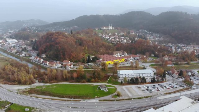 Wide angle dolly in drone shot of the beautiful city, of Celje, Jozefov Hrib/Saint Joseph's hill and the colourful buildings during the day