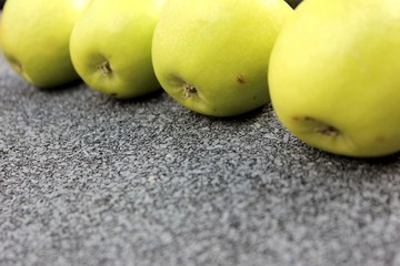 Yellow apples on a gray background. Row of green with one red apple among them on gray background. 4 Thinking out of the box concept. ripe green apples stone table background top view space for text
