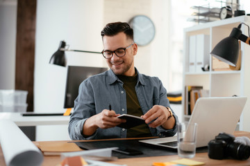Young handsome man working in office. Bussinesman working on lap top in office.