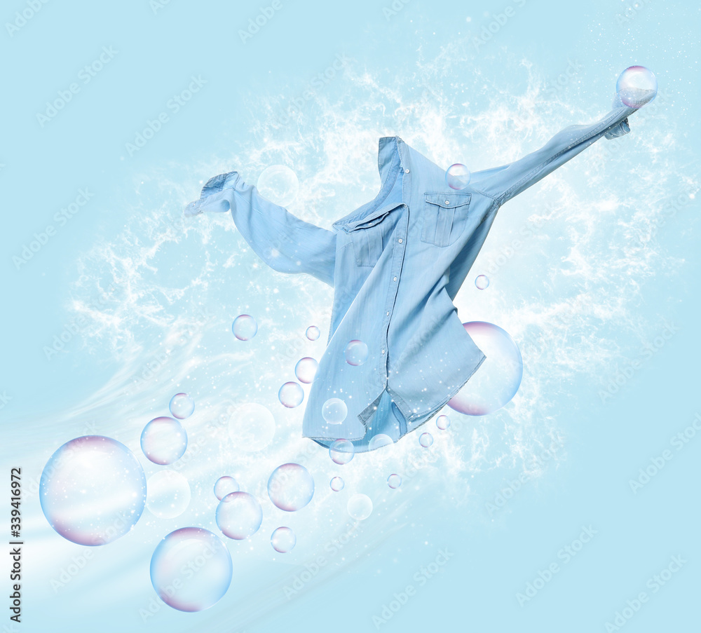 Wall mural Clean shirt with soap bubbles and water splash on color background - Wall murals