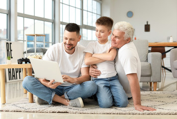 Man with his father and son using laptop at home