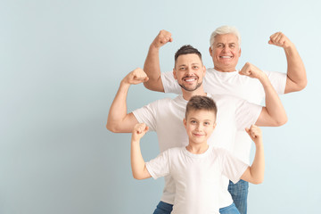 Fototapeta na wymiar Man with his father and son showing muscles on color background