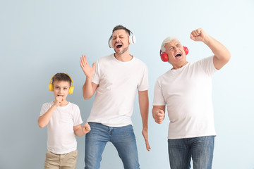 Man with his father and son listening to music on color background