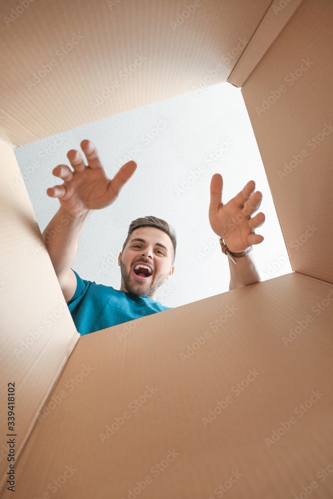 Wall mural Happy man with open box, view from inside