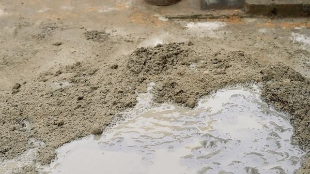 Indian labour mixing cement and water manually on floor using a shovel. Stcok footage.