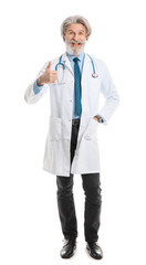 Portrait of senior male doctor showing thumb-up gesture on white background