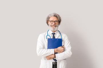 Portrait of senior male doctor on grey background