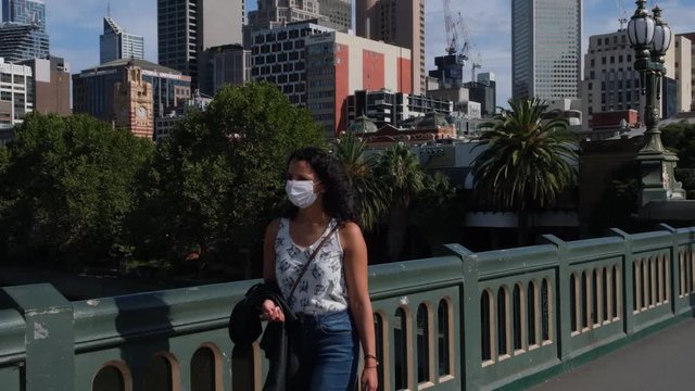 Woman with mask walking over Princes bridge during Covid19 Coronavirus