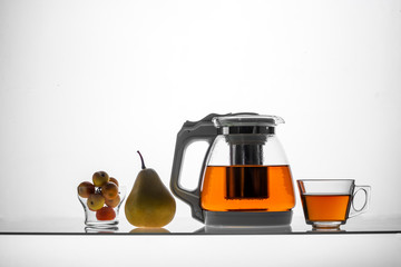 glass teapot and cup with hot tea on table, close view  