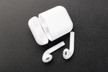 Modern wireless bluetooth headphones with charging case on a dark black background.