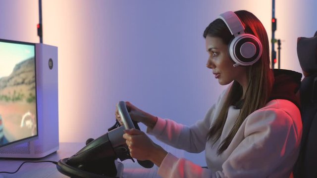 The young woman with headset plays video game in the blue light studio