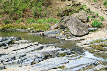 Children playing in the blue clear river. Rocks in the river.
