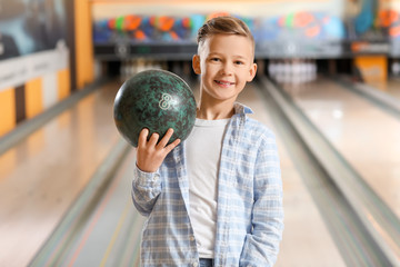 Naklejka premium Little boy playing bowling in club