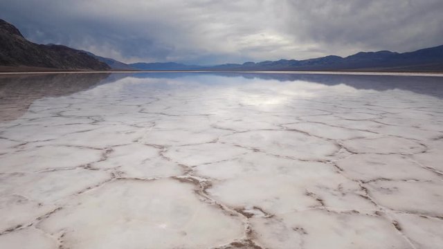 Walking in mirror surface of salt crust formations with water in Badwater Basin, Death Valley National Park. California, USA