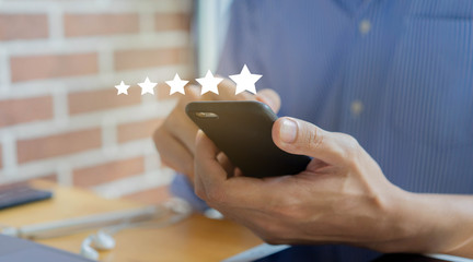 close up on customer man hand pressing on smartphone screen with gold five star rating feedback...