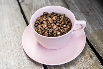 Close up of coffee beans in a cup, on a wooden table.