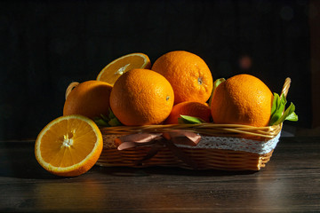 Basket of fresh oranges on a dark background.