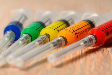 Concept photo of the COVID virus vaccine search. Syringes with different color filling.