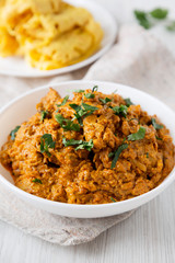 Homemade Chicken Tikka Masala in a white bowl on a white wooden background, low angle view. Close-up.