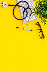 Doctor office desk with keyboard. Yellow table top view copy space